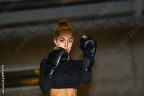 Woman smiles while wearing a pair of boxing gloves © JeanPaul