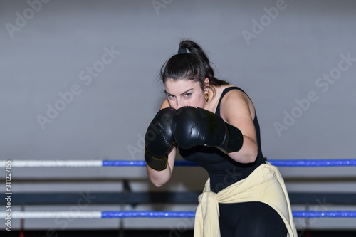 Focused woman in boxing gloves guards herself