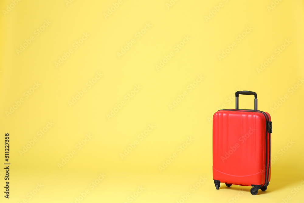 Stylish red suitcase on yellow background. Space for text Stylish red suitcase on yellow background. Space for text