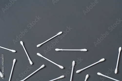Scattered many new cotton sticks for hygiene lies on dark concrete desk. Space for text. Top view
