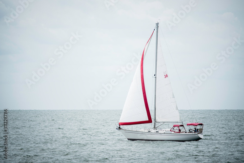 white sailboat sailing a red and white sail