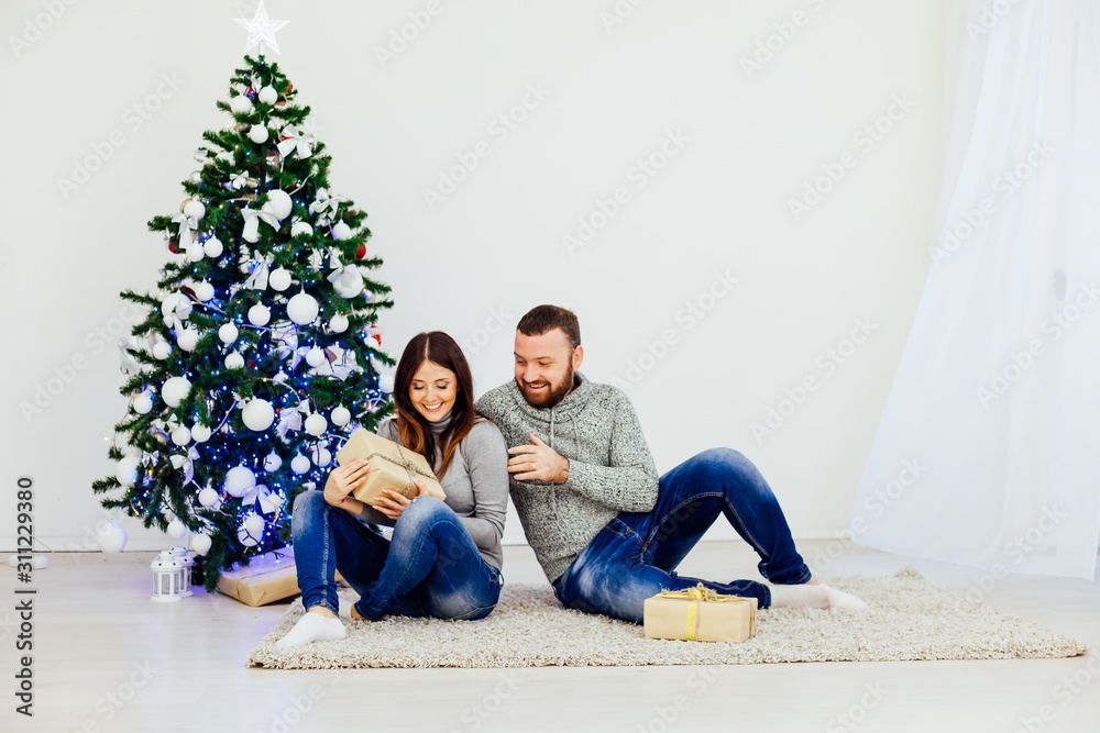 husband and wife on Christmas trees offer gifts for the new year