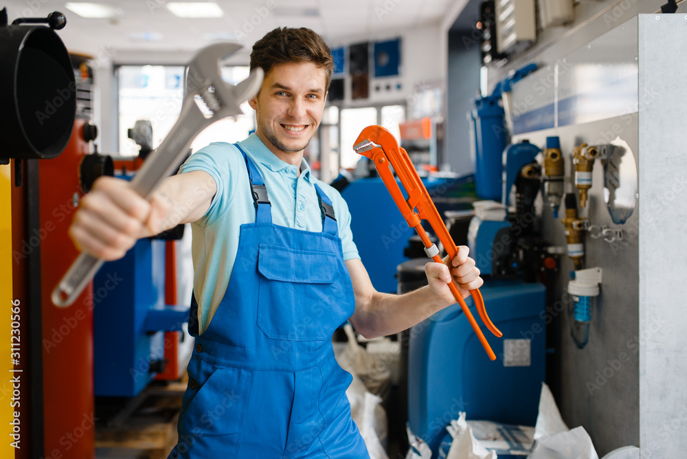 Fototapeta premium Plumber shows pipe wrenches in plumbering store