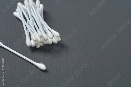 Heap of new cotton sticks for hygiene lies on dark concrete desk. Space for text © OlekStock