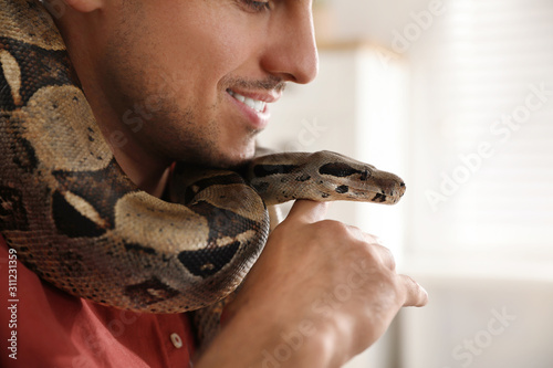Man with his boa constrictor at home, closeup. Exotic pet photo