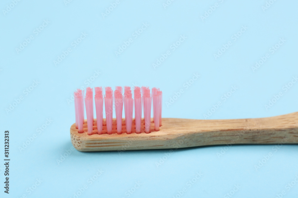 Toothbrush made of bamboo on light blue background, closeup Toothbrush made of bamboo on light blue background, closeup