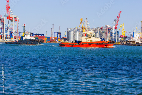 tugboat in the port of Odessa on the black sea against the background of an industrial terminal. Merchant ships on loading