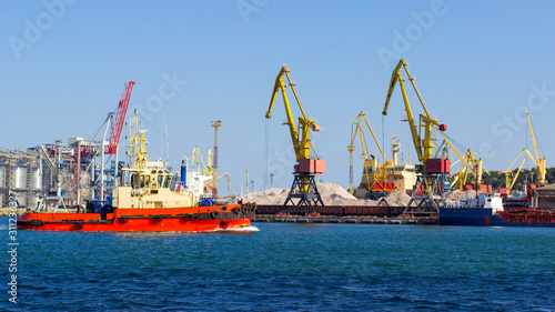 tugboat in the port of Odessa on the black sea against the background of an industrial terminal. Merchant ships on loading © stason4ik