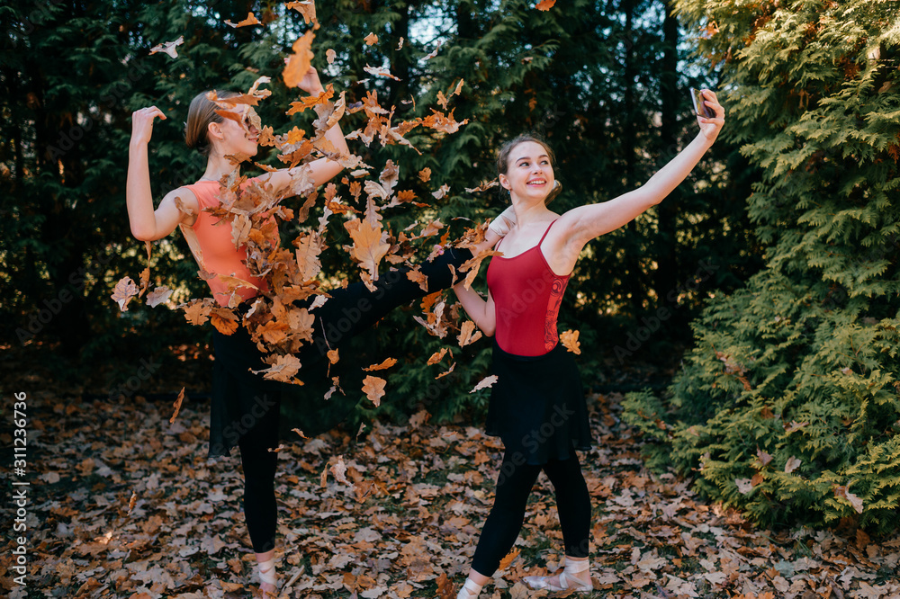 Two cheerful ballerinas taking selfie standing under falling leaves in park  Stock 写真 | Adobe Stock