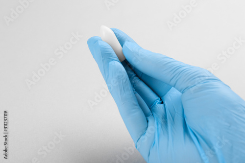 Woman holding suppository on light background, closeup. Hemorrhoid treatment