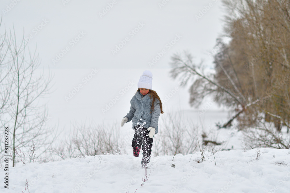 Happy child girl on winter walk outdoors . little child playing in winter holidays. Girl in winter lake