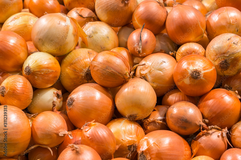 Fresh yellow onions as a background. Vegetable store. Yellow onion lies in a box in a store for sale Fresh yellow onions as a background. Vegetable store. Yellow onion lies in a box in a store for sale