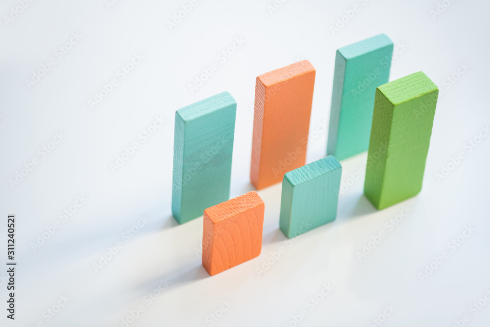Two parallel rows of blue, orange and green flat wooden bricks making up charts Two parallel rows of blue, orange and green flat wooden bricks making up charts