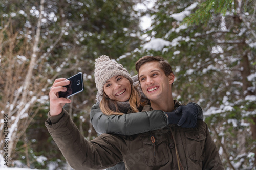 man and woman taking a selfie in the forest covered by snow © NDStock