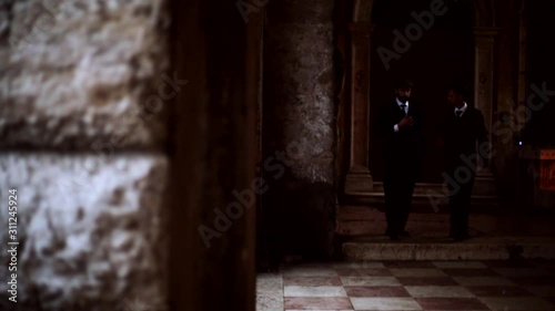 Business men vintage talking and walking on long hallway in palace.