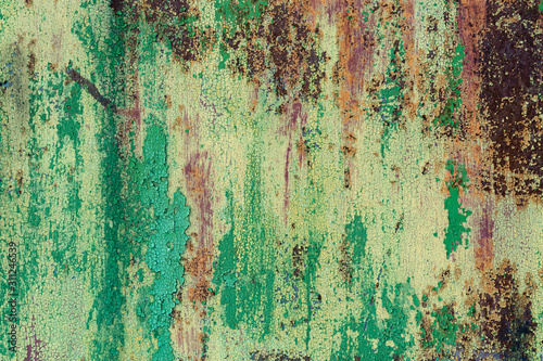 Old metal rusted green-yellow sheet with bounced, cracked paint. Abstract colorful texture background.