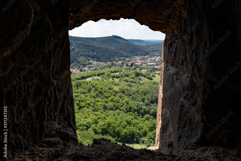 View of a valley through the stone window of a medieval fortress in europe-2