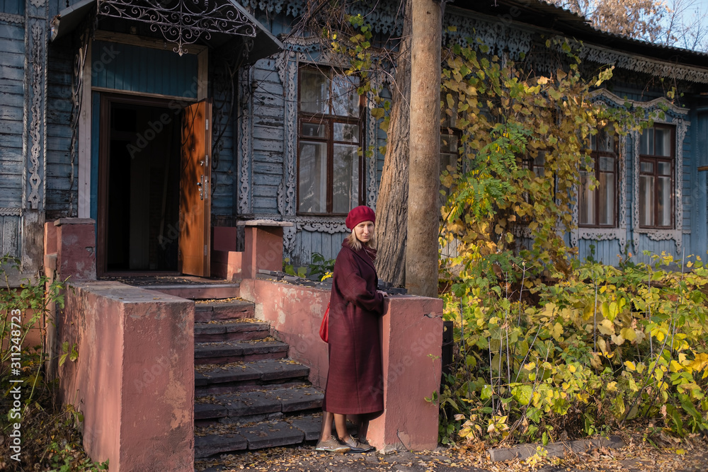 Fototapeta premium A woman stands on the porch of an vintage country house.