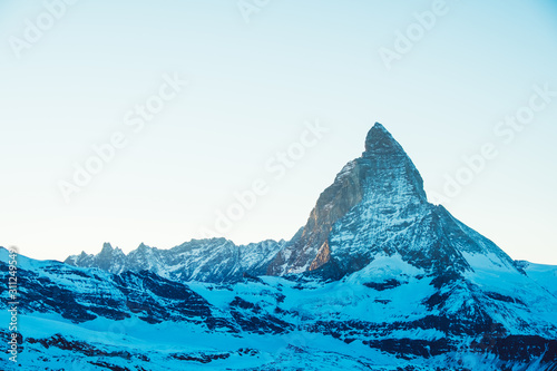 Scenic view on snowy Matterhorn mountain peak in sunny day with blue sky, Zermatt, Switzerland. Beautiful nature background of winter Swiss Alps covered with snow. Famous travel destination.