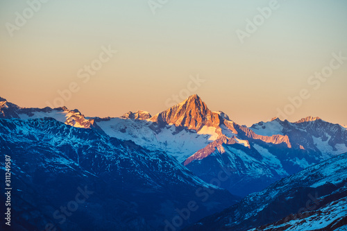 Beautiful nature landscape of Swiss Alps in sunlight rays. Sunset mountains covered with snow in Switzerland. Great view of the snowy rocks and sun beams in Alpine ski resort. Winter holidays. © YOUproduction