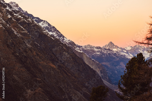 Beautiful nature landscape of mountains and colorful sunset in Swiss Alps, Switzerland. Great view of sun light shining on snowy rocks in Alpine ski resort Zermatt near Matterhorn. Winter background.