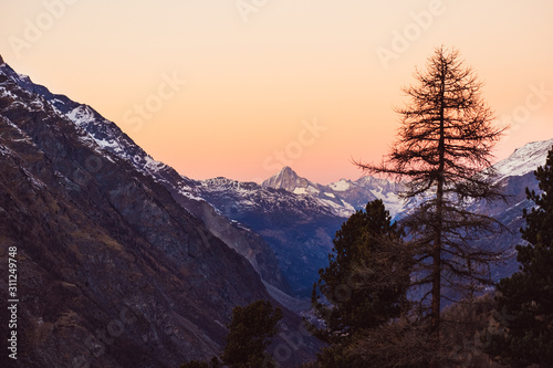 Beautiful nature landscape of mountains and colorful sunset in Swiss Alps, Switzerland. Great view of sun light shining on snowy rocks in Alpine ski resort Zermatt near Matterhorn. Winter background.