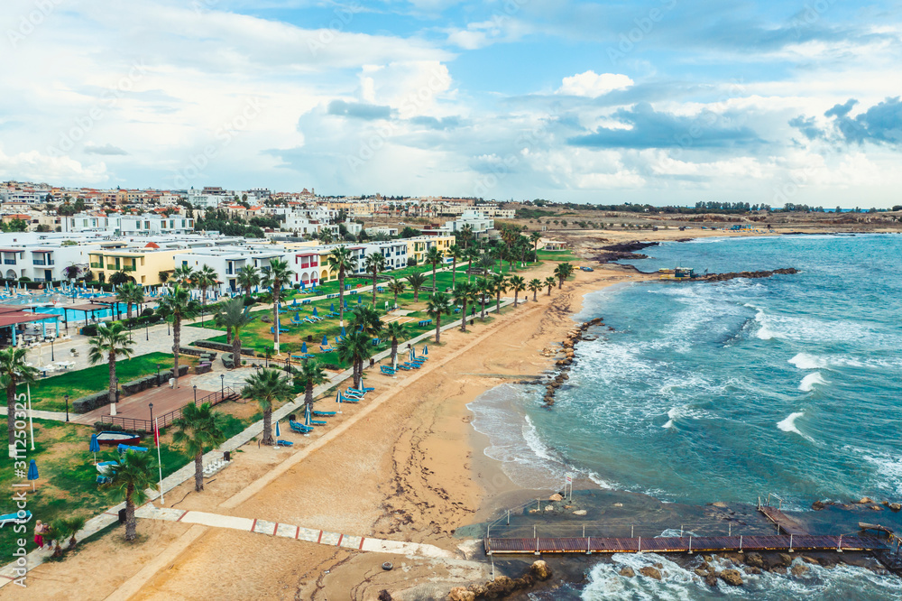 Paphos embankment or promenade, Cyprus, with sandy beach, green palm trees and lawns and small houses on first coastline, aerial view from drone