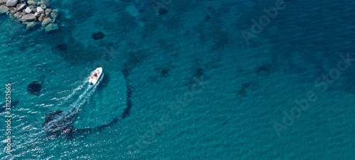 Photography Aerial drone top view photo of small boat cruising in tropical exotic bay with t