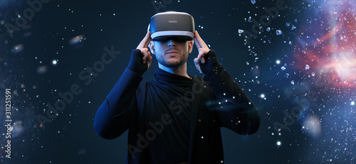 Young man on virtual reality background. Guy using VR helmet. Augmented reality, future technology, game concept.