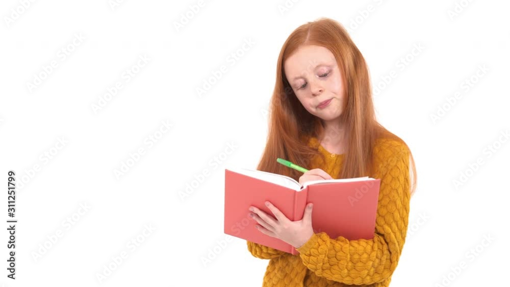 Cute school girl writing notes to workbook. Thoughtful girl is studying. Educational concept Cute school girl writing notes to workbook. Thoughtful girl is studying. Educational concept