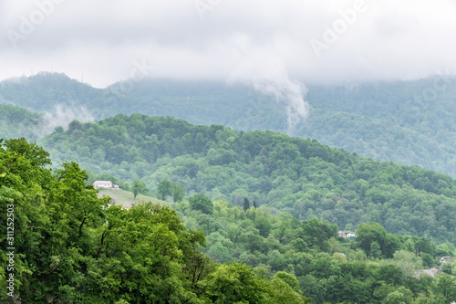 Layers of mountains in the haze in rayny day. Fog in a hilly valley with villages