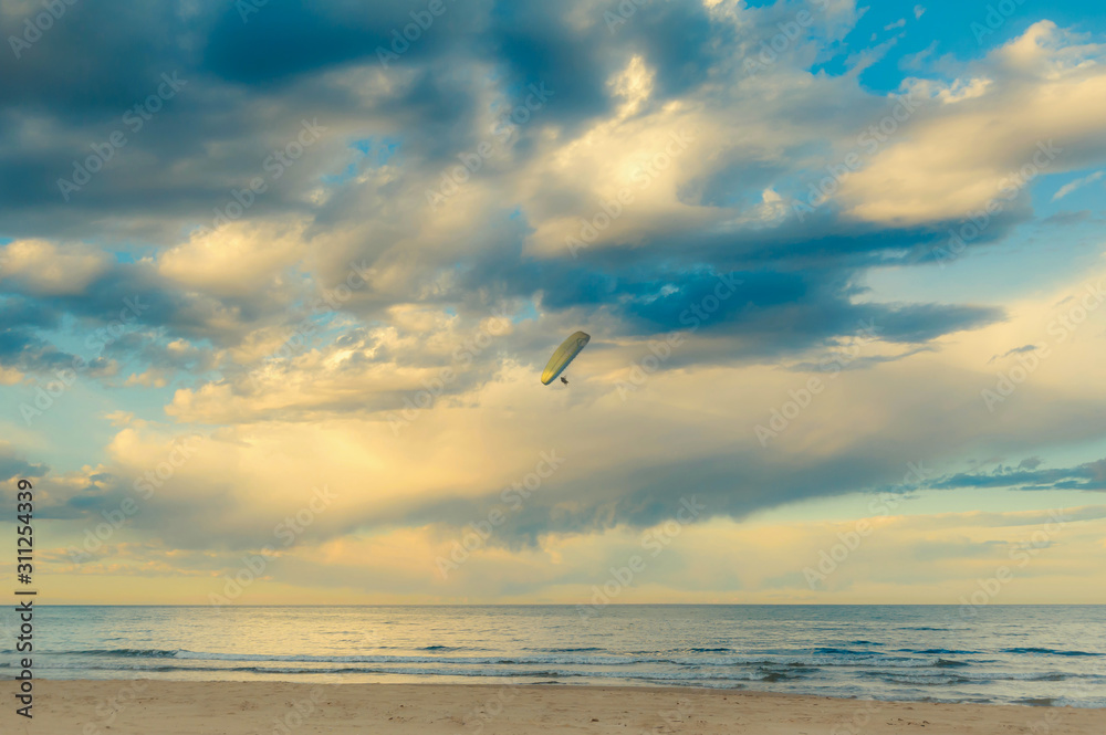 Seascape with glider in the sky during sunset.