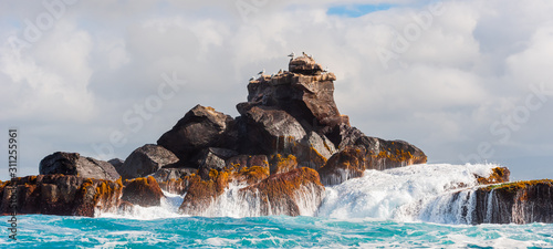 Rock in the ocean on a background of the cloudy sky, Galapagos Island, Isla Isabela.