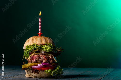 single cheeseburger with a burning candle