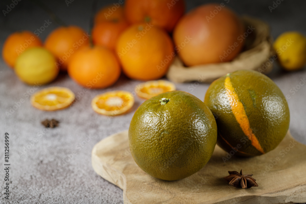 Ripe sweet green oranges for winter desserts and juices. Two oranges on a wooden board