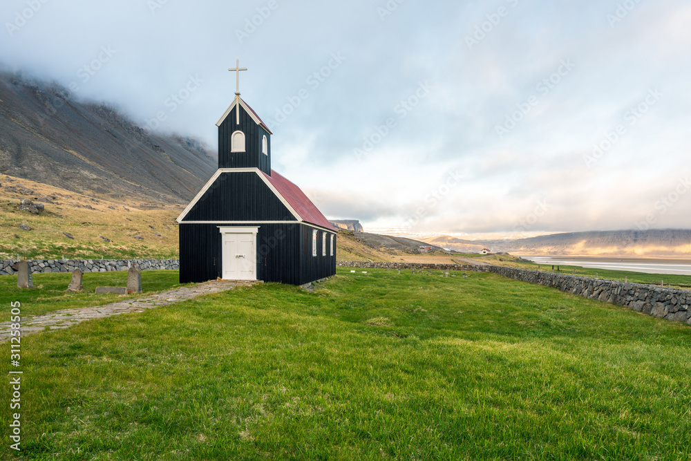 Old ancient wooden church called Saurbæjarkirkja in Raudasandur beach in Iceland. Tiny church among mountains and beaches in the westfjords of the Icelandic wilderness. Traveling and explorer concept.
