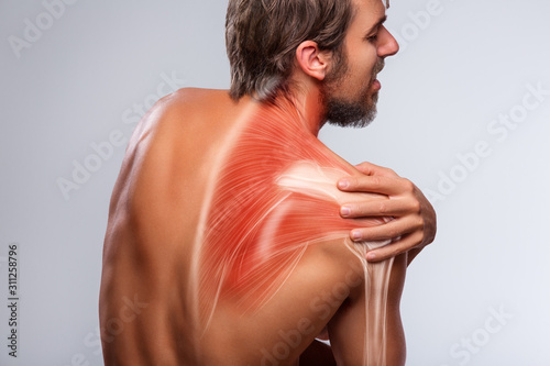 Shoulder pain. Man holding a hand on shoulder photo