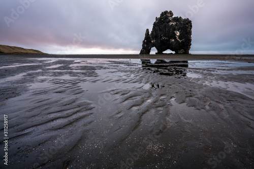 Sandy textured beach at low tide with the basalt/volcanic rock named hvitserkur in the vatnsnes peninsula in the nort western part of Iceland. Traveling backpack concept. photo