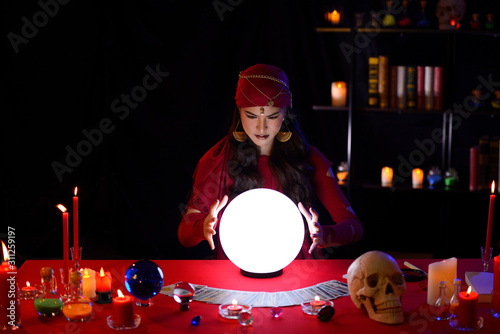 Fortune-teller woman is predicting with a shining crystal ball
