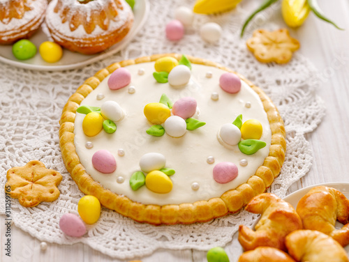 Mazurek pastry, traditional Polish Easter cake made of shortcrust pastry with  white chocolate cream, decorated with marzipan eggs  and sugar pearls on the holiday table,  close-up.  Sweet dessert