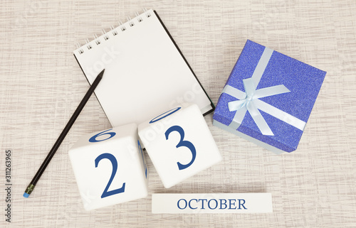 Wooden calendar for October 23, gift box in classic blue with a white ribbon, trend color numbers