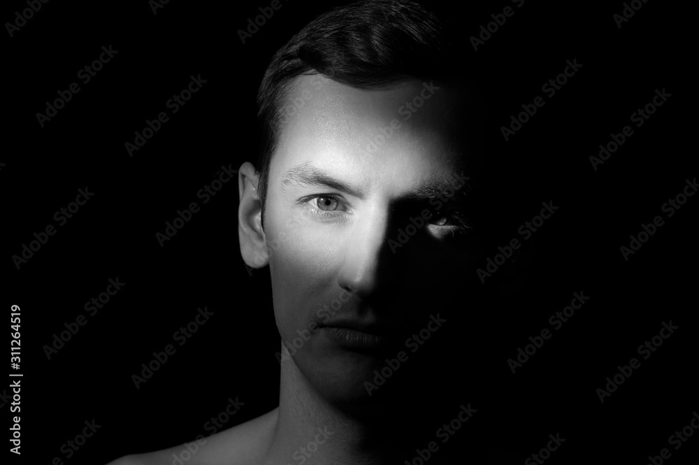 black and white dramatic portrait of a guy close-up on a black background with one light source