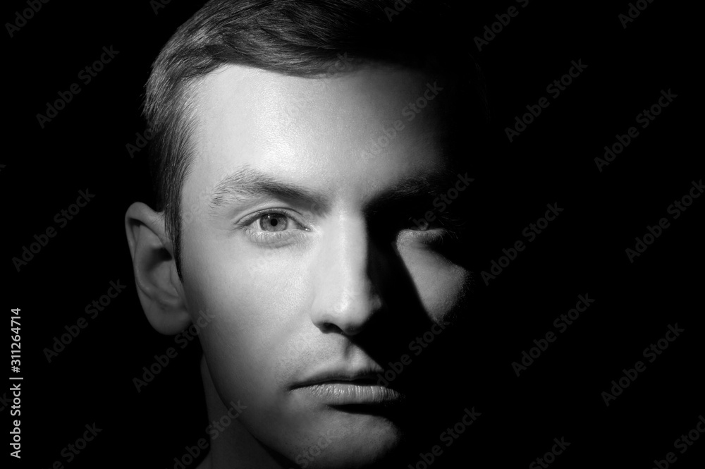 black and white dramatic portrait of a guy close-up on a black background with one light source