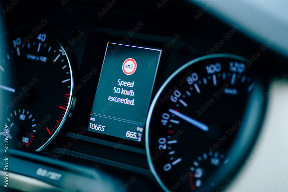 Speed limit exceeded signage on the digital screen dashboard of a new car