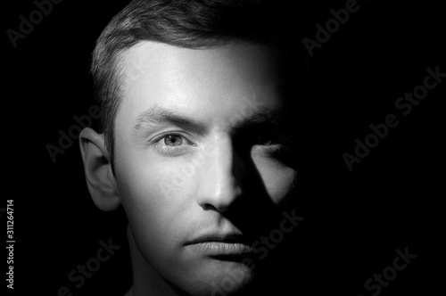 black and white dramatic portrait of a guy close-up on a black background with one light source