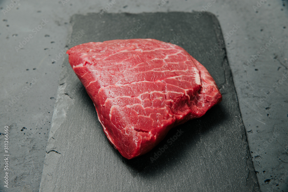 Raw beef, beef steak on a stone background. The concept of preparing a meal and eating. Fresh