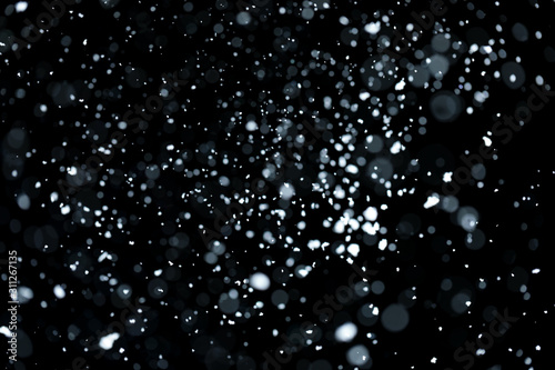 Blurry bokeh of falling white snow on black background