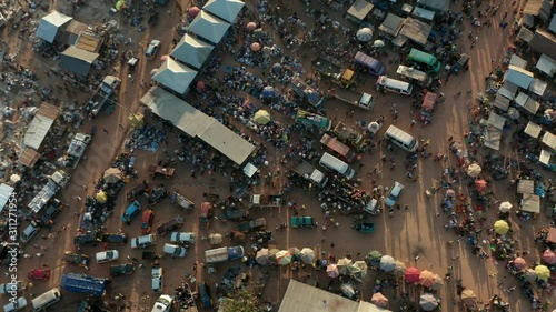 Aerial top down drone shot of African market in Ghana. A big group of Africans trading and walking with buckets on heads.
