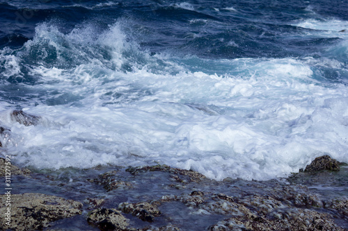 Blue atlantic ocean, white foam and volcanic rock