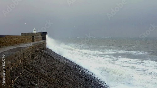 Waves crashing onto sea defences Porthcawl lighthouse South Wales during storm Atiyah in slow motion photo